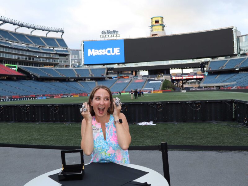 Woman standing on field at Gillette Stadium wearing super bowl rings