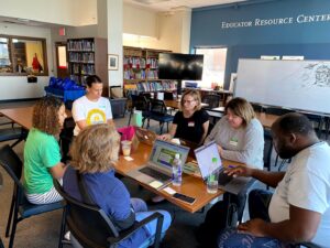 A group of individuals discussing a slideshow at a table together.